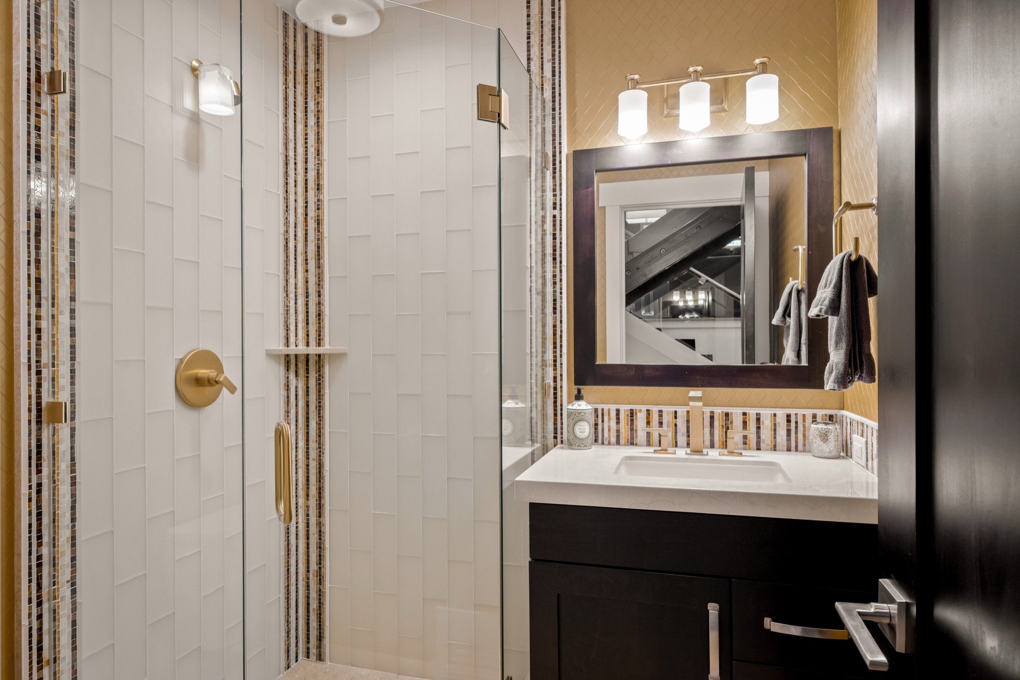 Bath — vertical white textured tile shower, dark vanity, brass fixtures